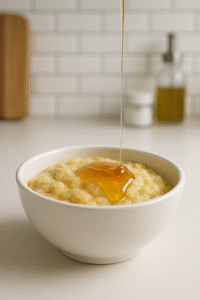 Tigela com banana amassada e mel sendo derramado.